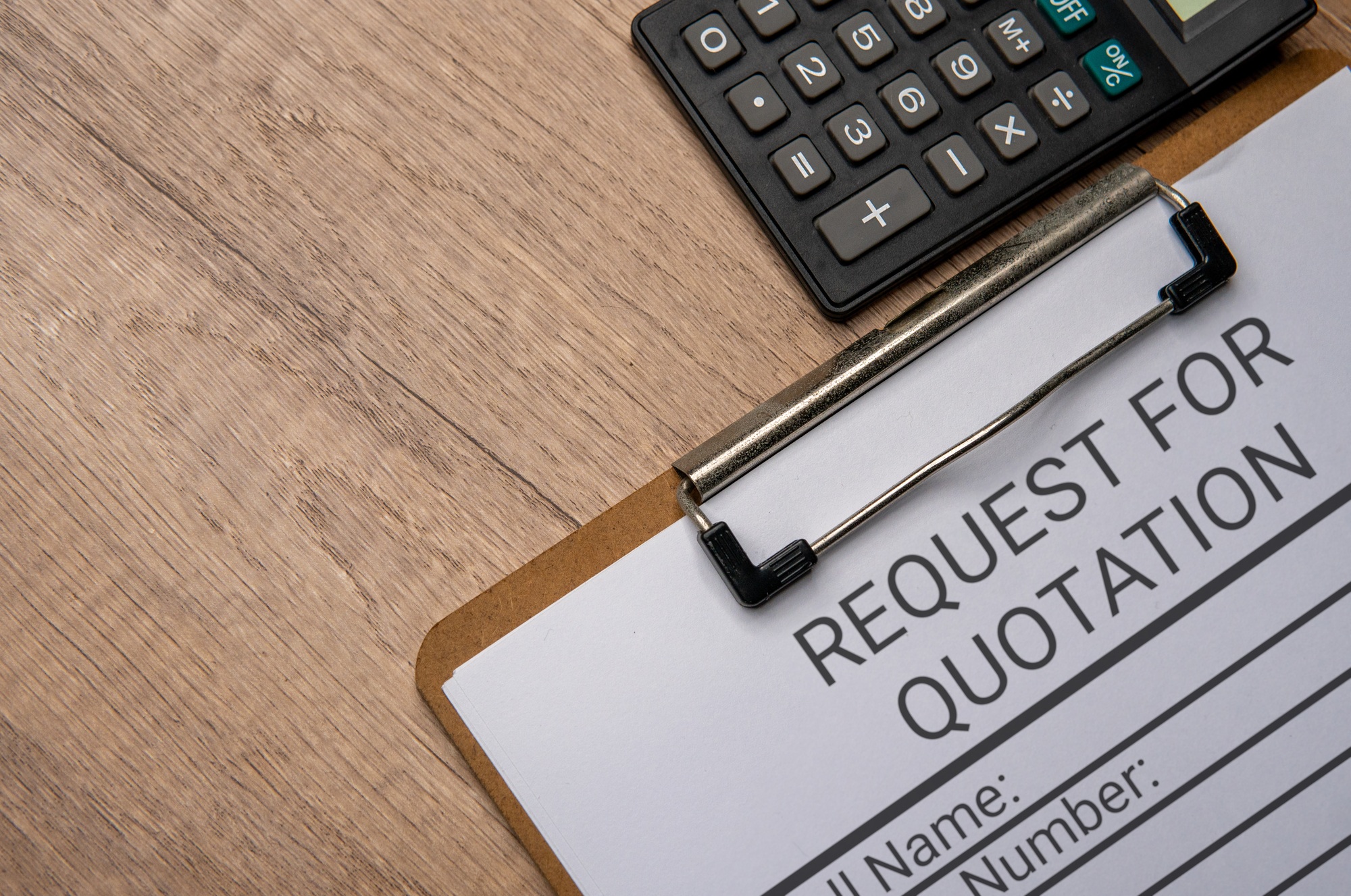 A clipboard with a paper titled “REQUEST FOR QUOTATION” and a black calculator.